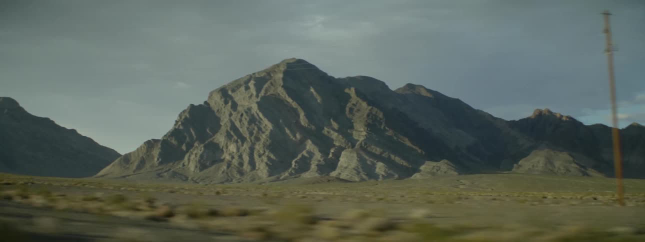 Power lines line the field before this mountain