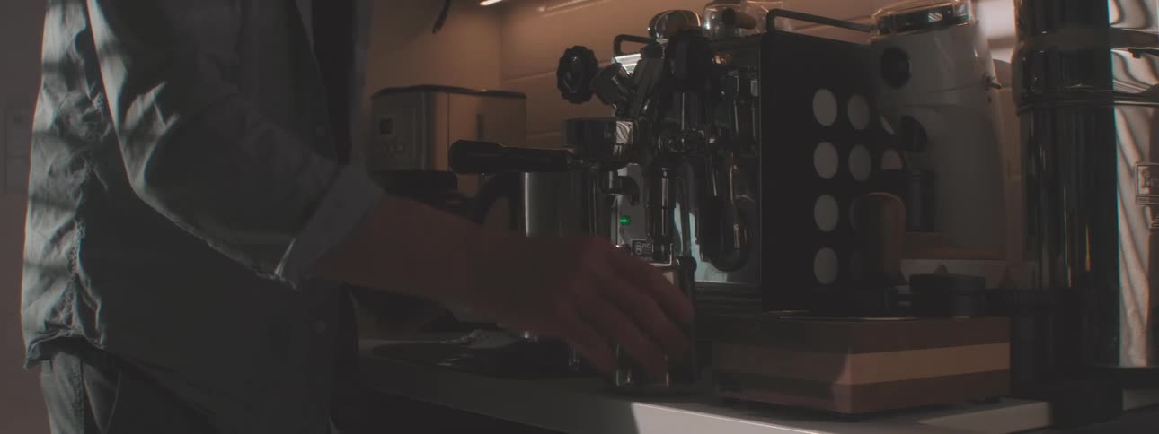 The man makes a cup of coffee with the large coffee machine