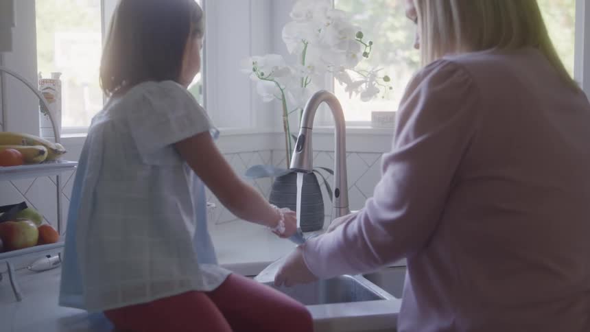 The mother and daughter wash dishes together