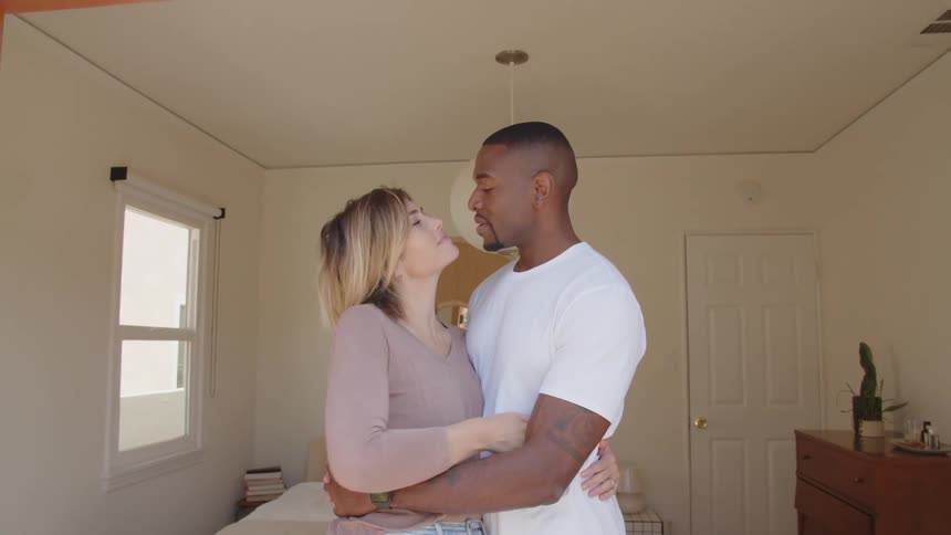 The couple hug and kiss in the bedroom