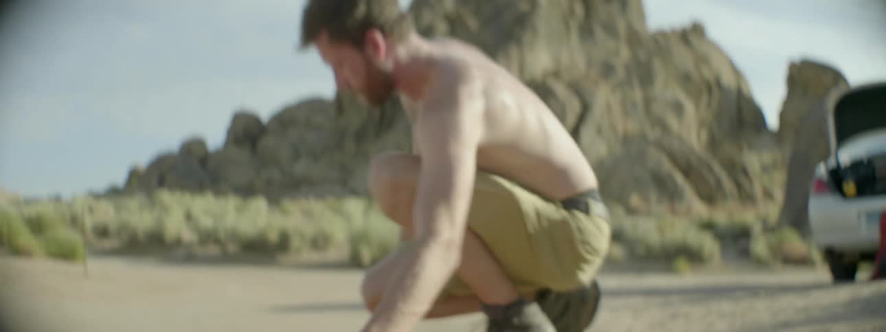 A man is folding up a tent on the sand