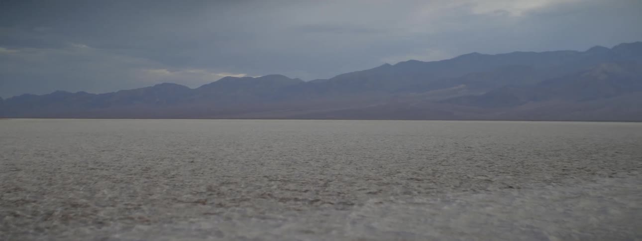 A long barren field leads to a mountain
