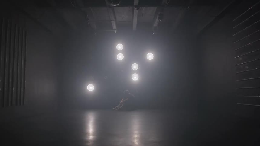 Pattern of flashing circular lights illuminates a person sitting on the floor in a dim room