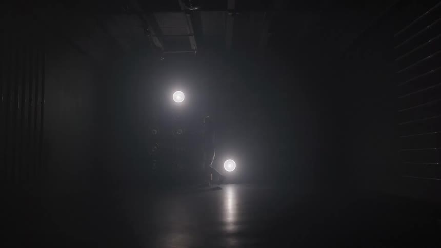 The video is a wide shot of a dark empty room or studio where six circular white lights are attached to the ceilingthe lights are brightly glowing and arranged in a rough circular pattern in the center of the frame against the otherwise black
