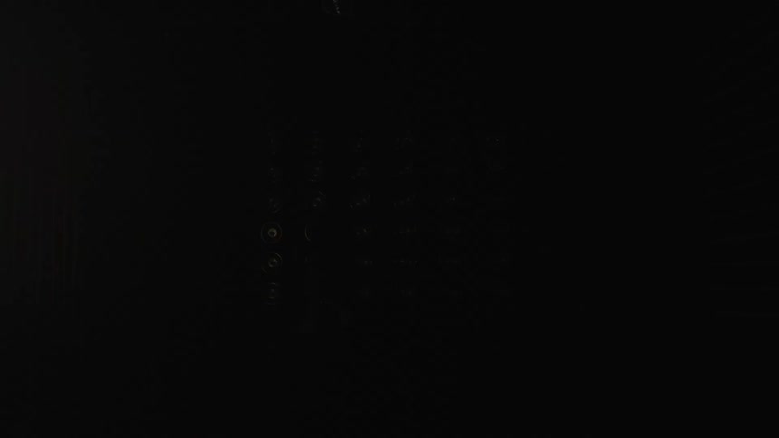 Circular lights illuminate reflective floor as person walks in dark setting