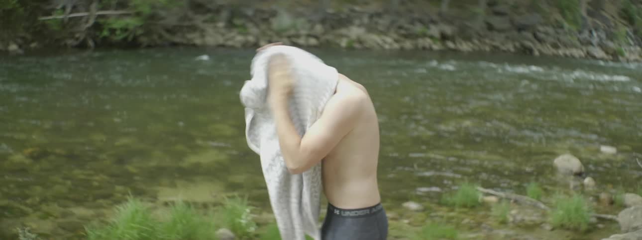 Man drying his hair with towel next to river