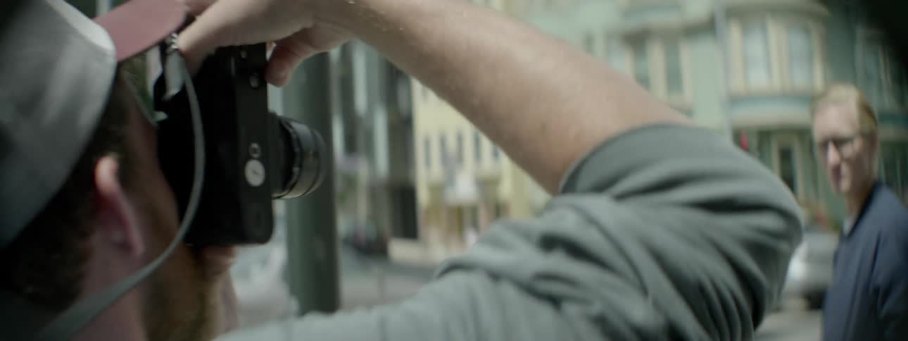 A man poses for a photograph on a street corner
