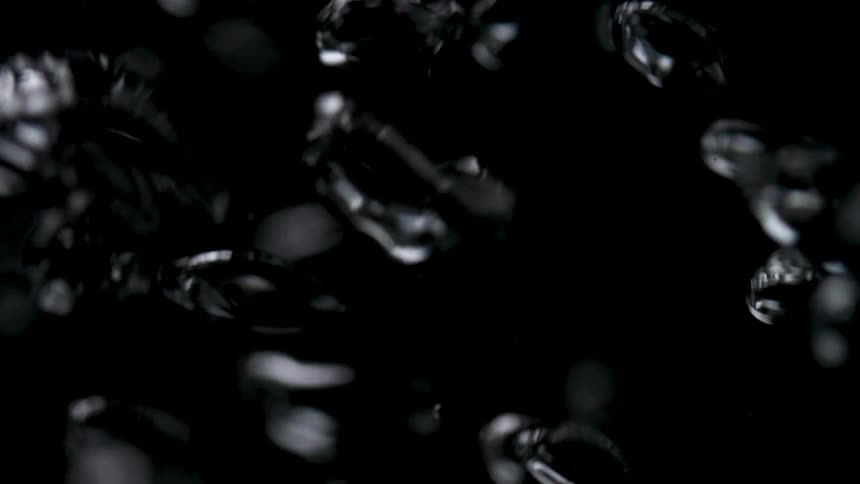 A cluster of glossy abstract shapes glints against a black background