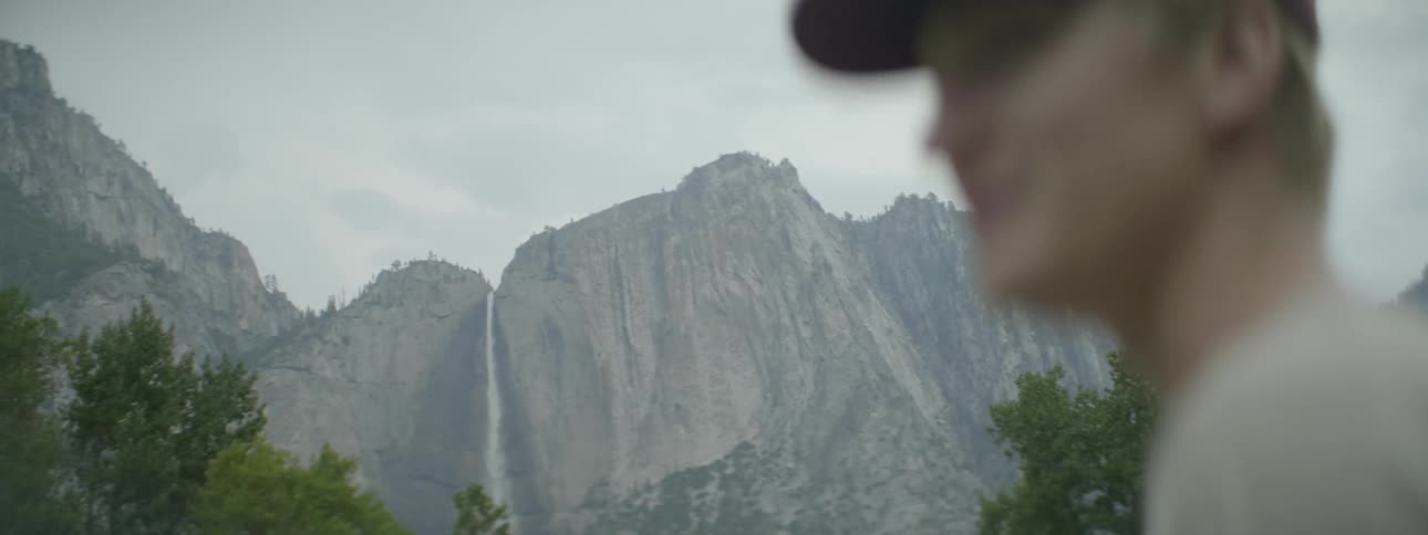 A man looks out over a mountain range and turns around