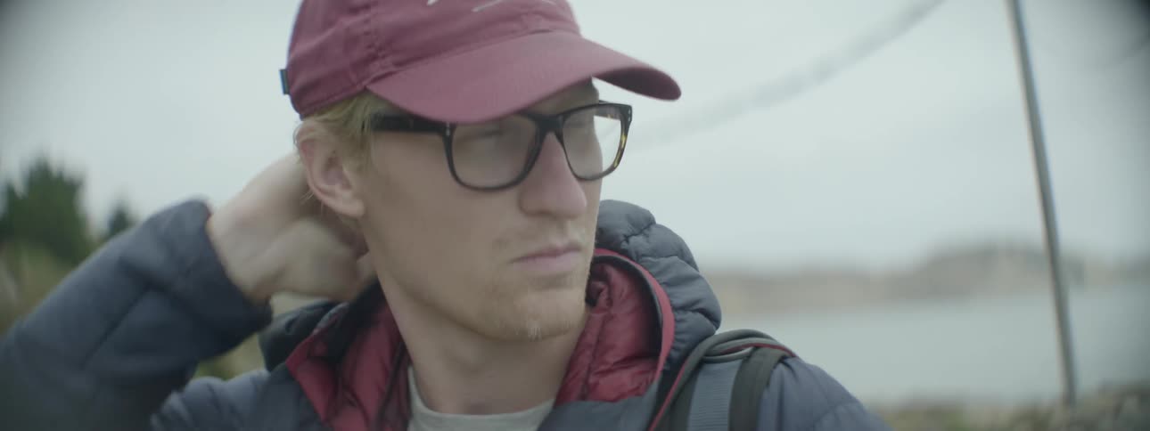 A man wearing glasses adjusts his cap