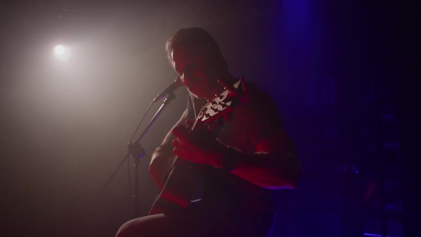 The spotlight shines on the guitarist playing music on stage