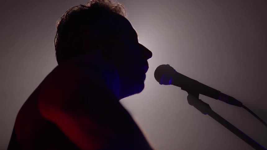 The man is singing under the spotlight