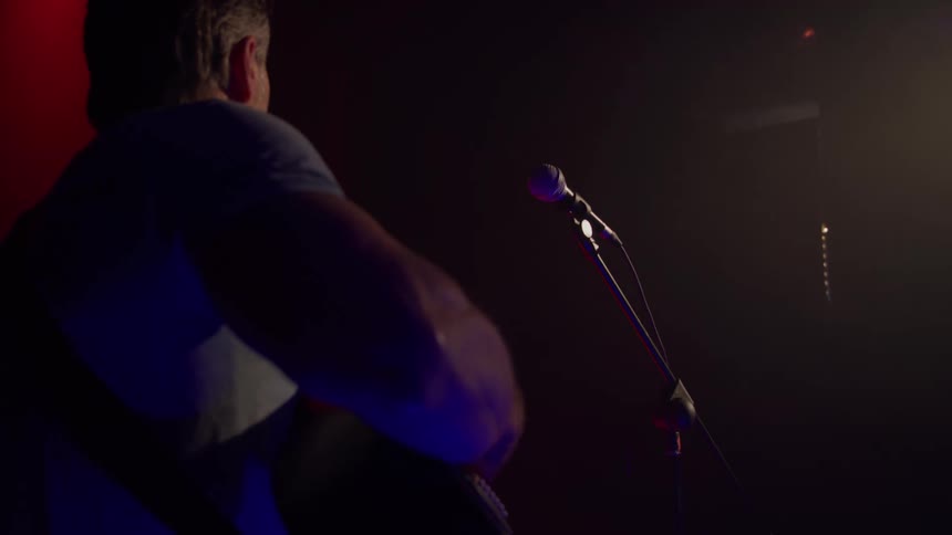 Musician plays the guitar on stage as he performs
