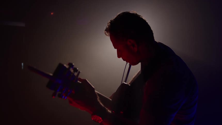 Musician plays the guitar on stage as he performs in concert
