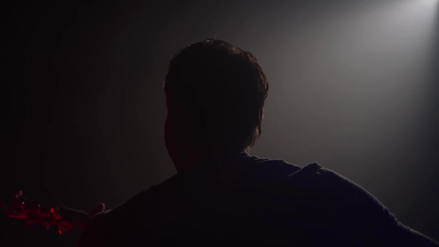Male guitarist performs on stage in a dimly lit room
