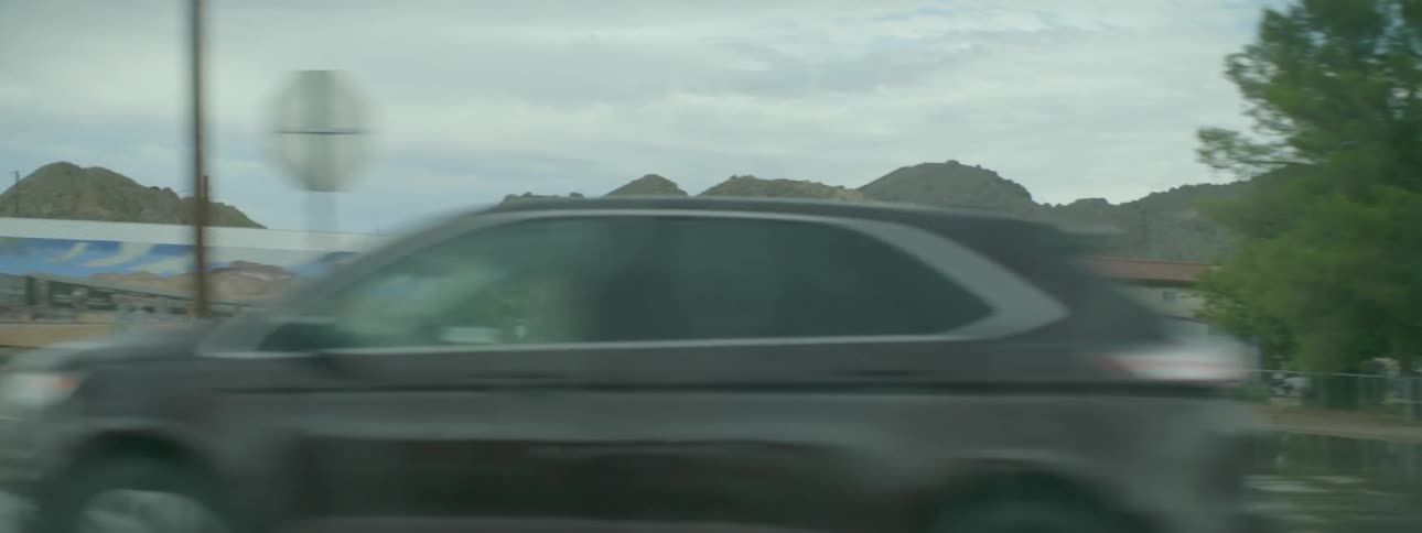 A vehicle drives by rural houses and buildings