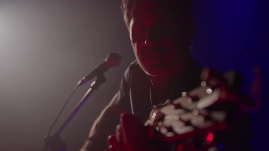 Musician playing a guitar as he performs on stage