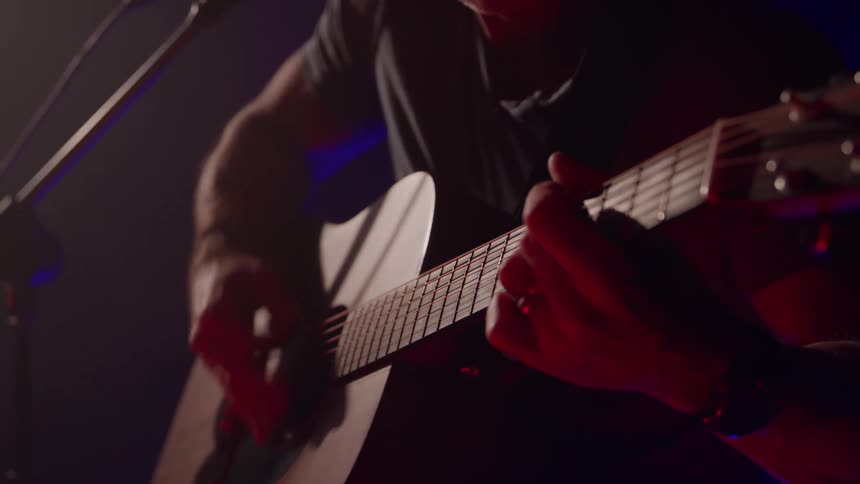 Musician plays an acoustic guitar as he performs on stage