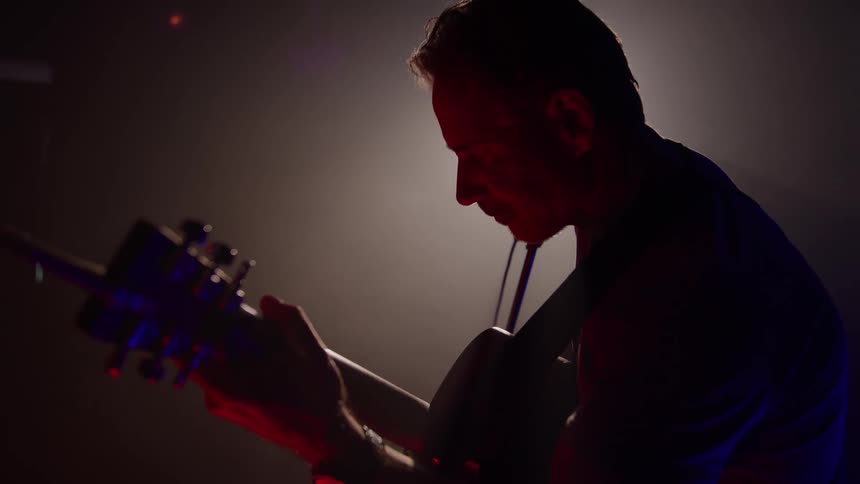 Musician plays the guitar on stage as he performs