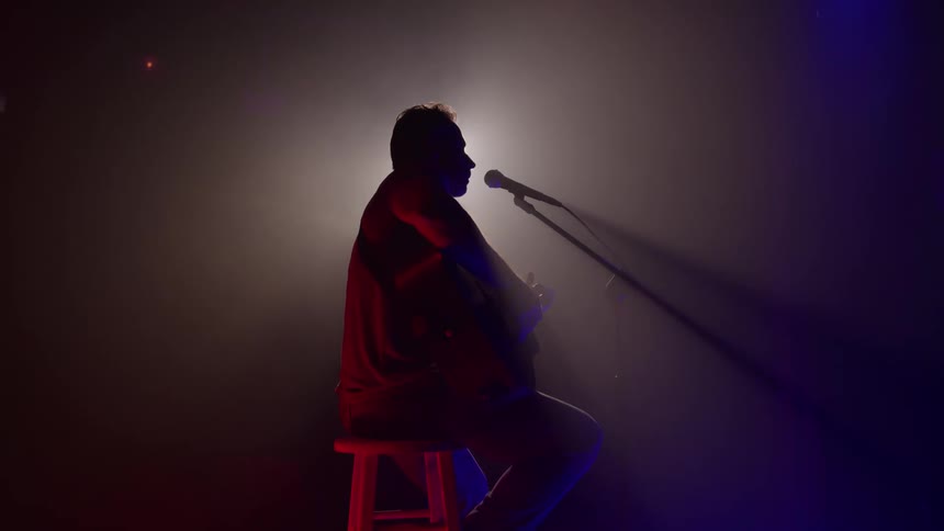 Man sings and plays the guitar during a performance