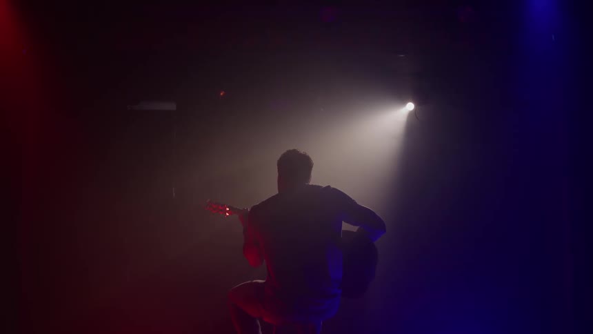 Musician plays the guitar on stage as he performs