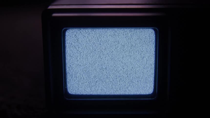 An older model television is displaying only flickering static on its screen