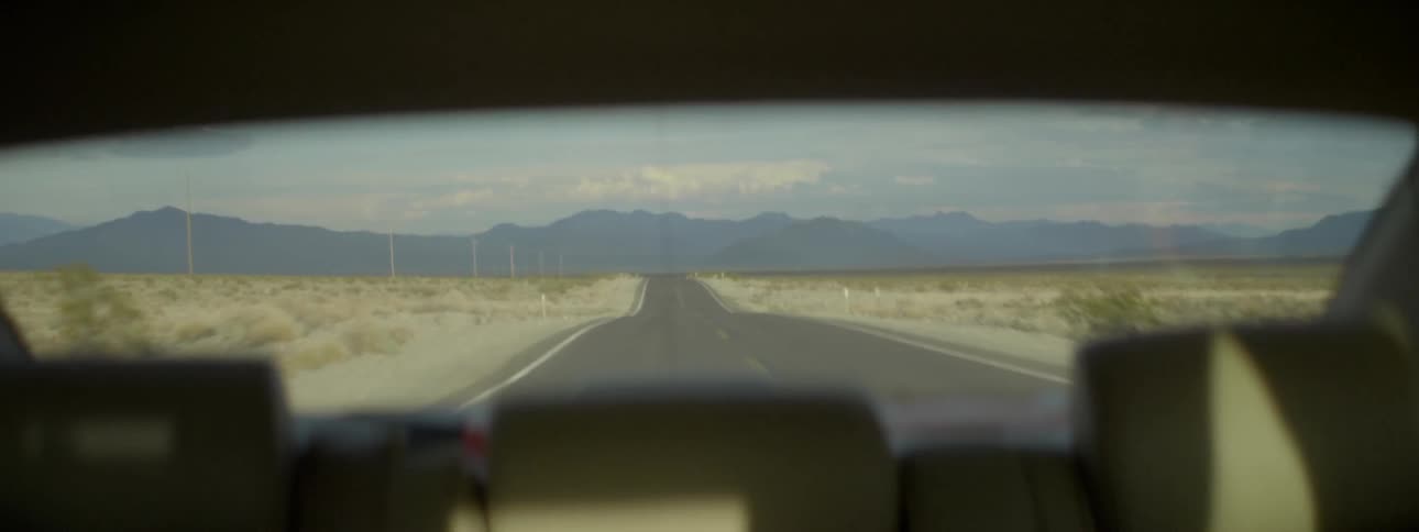 View looking out the back of a car as it travels down a country road