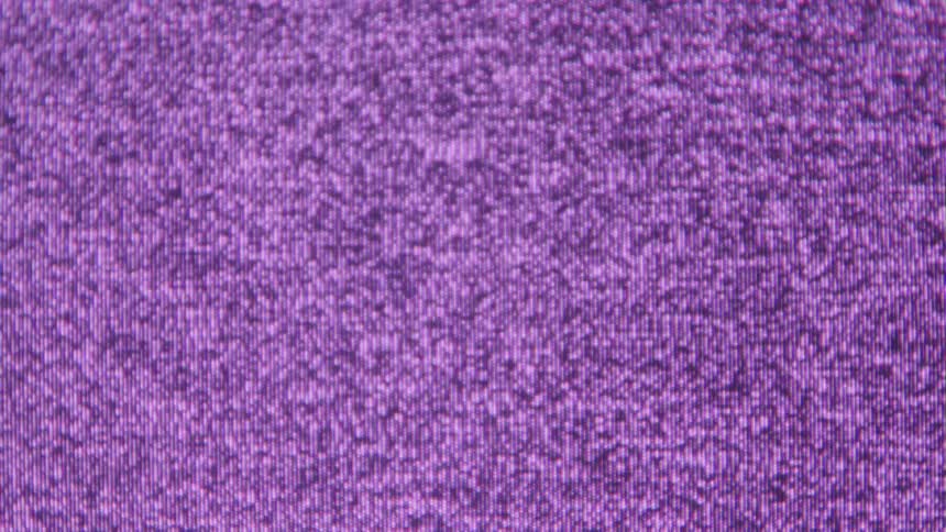 Close up of an electronic device displaying a purple static screen