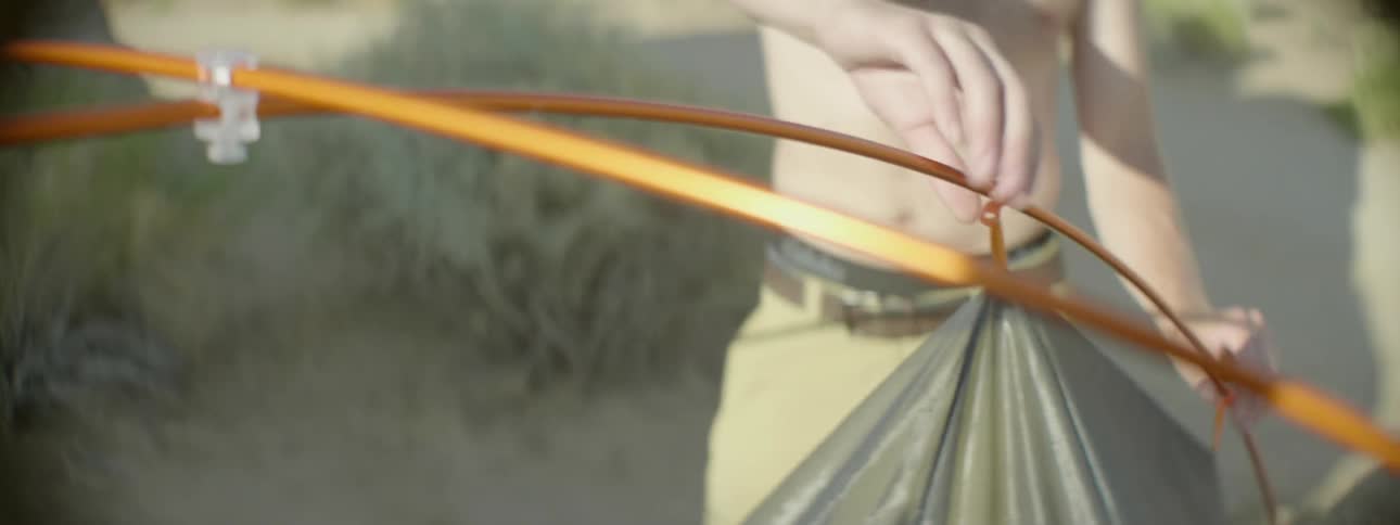 A shirtless man takes down a tent