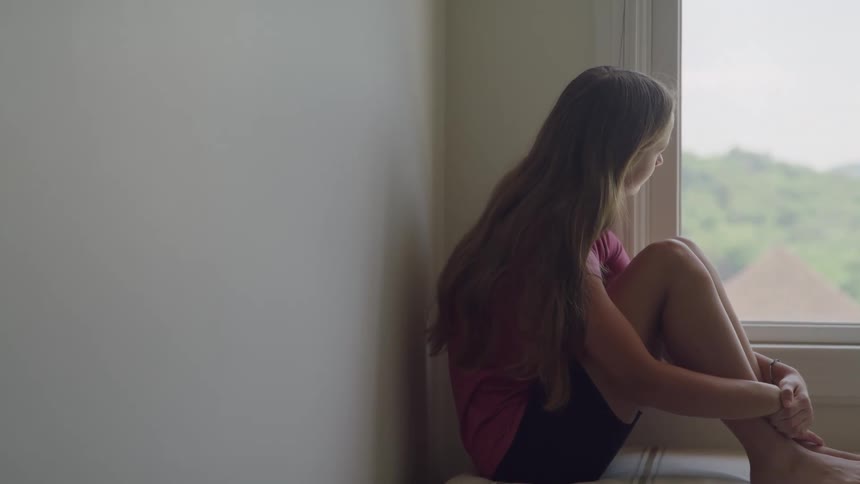A teen girl is sitting near the window watching the scenery