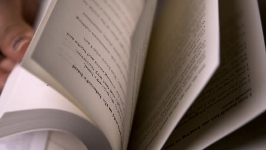 The video is an extreme closeup of a persons hands flipping through the pages of a small textheavy bookthe pages contain lines of what appears to be poetry including the visible phrase your face all night