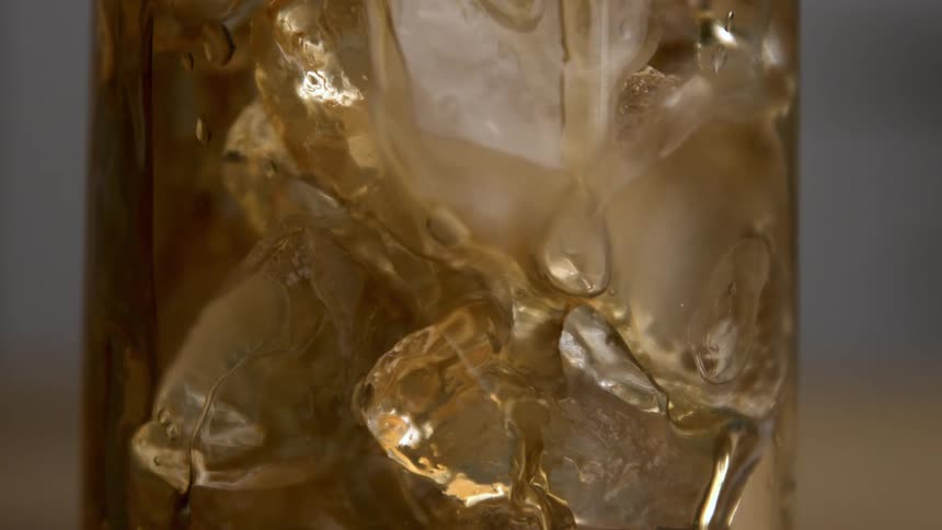 The glass full of ice is being filled