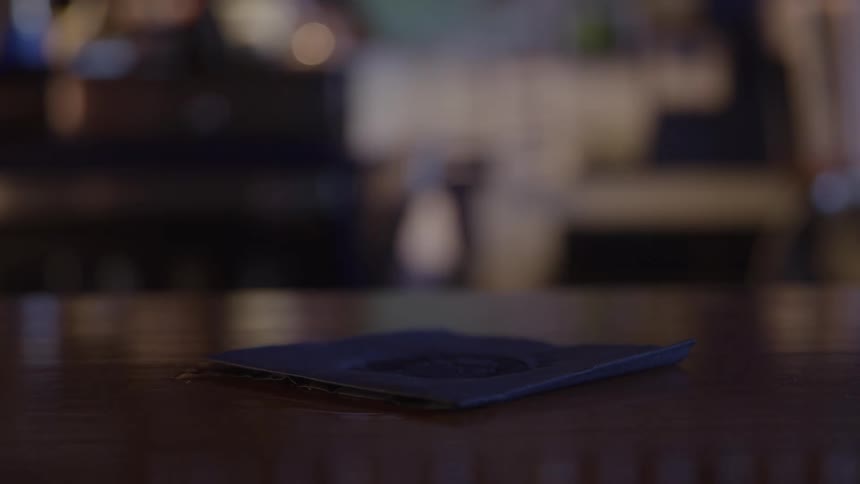 A person picks up a drink off a wooden table