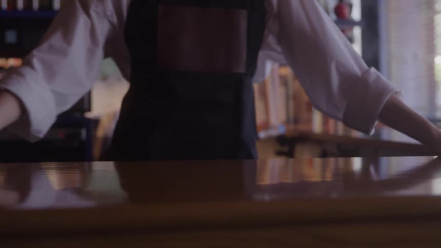 A waitress is using a cloth to wipe the restaurant table clean