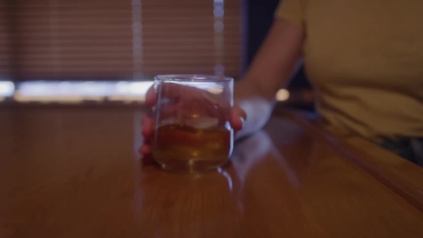 The bartender slides a drink to the woman