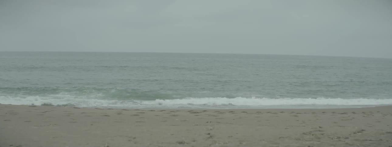 Waves rolling up onto beach on overcast day
