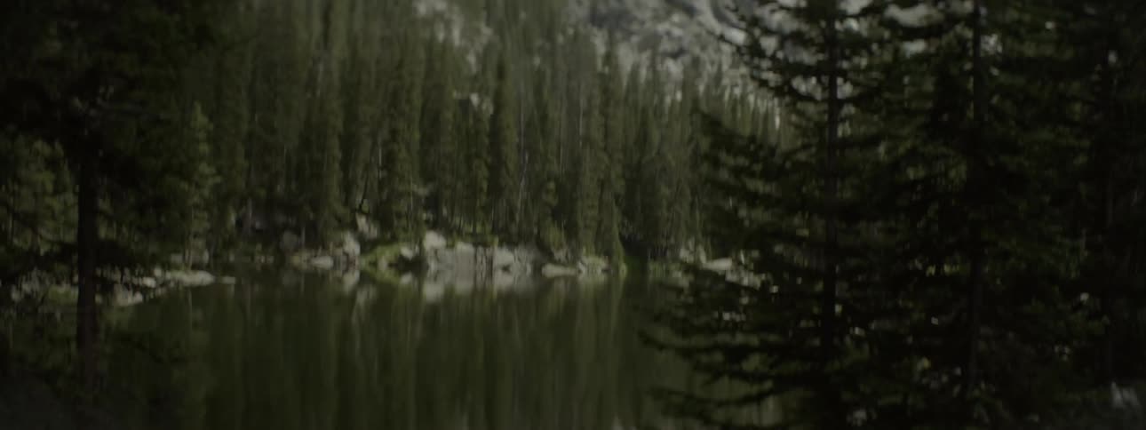 A lake ripples in front of a rocky mountain peak