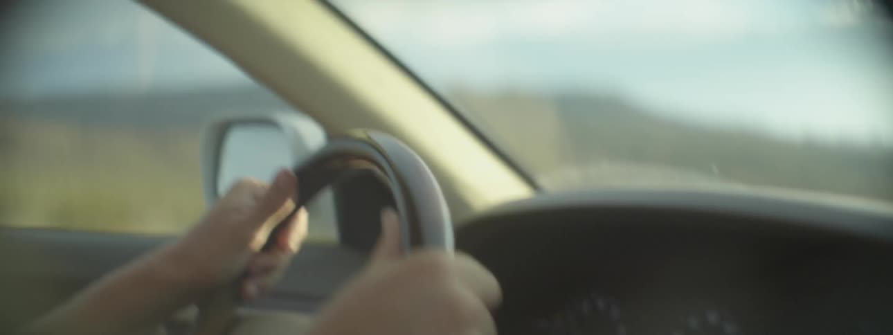 Two hands on the steering wheel of a car