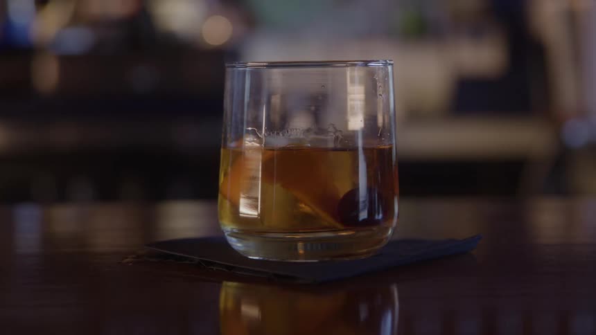 A person puts an alcoholic drink in a glass on a table
