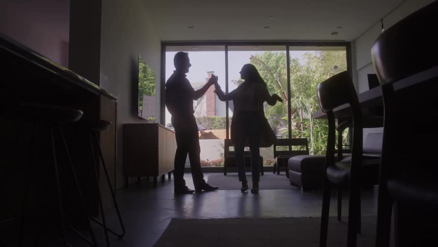 The man and woman dance in their living room