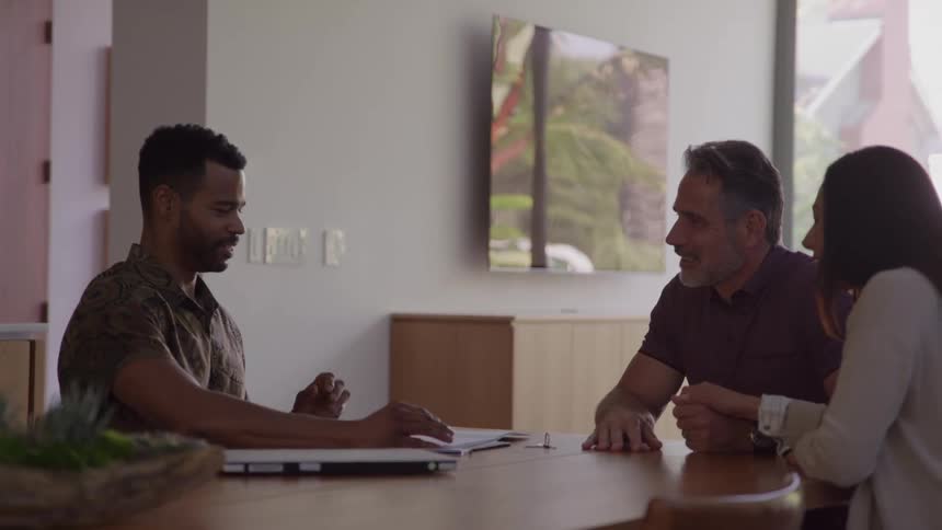 A real estate agent discussing documents with a couple in a modern home