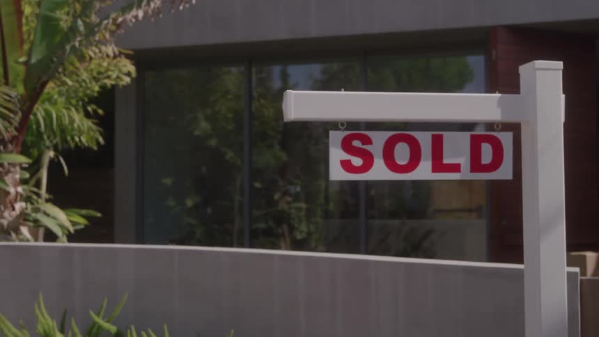 A sign outside a suburban home reads sold at midday