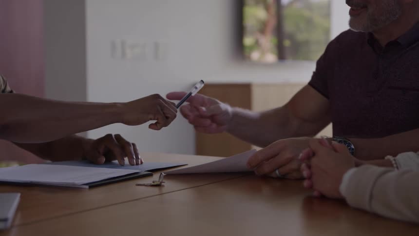 Salesman hands paperwork over to be signed by a customer making a large purchase