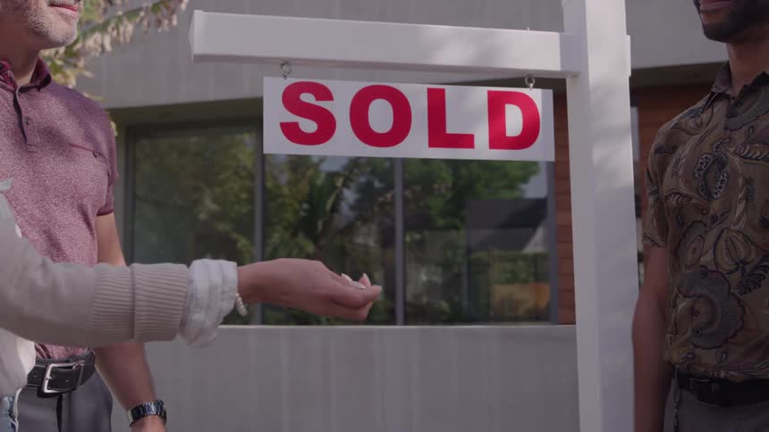 Real estate agent handing happy buyers keys to newly purchased home