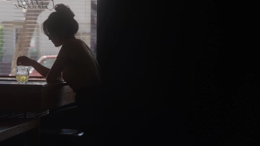 Depressed woman drinking beer alone at a bar
