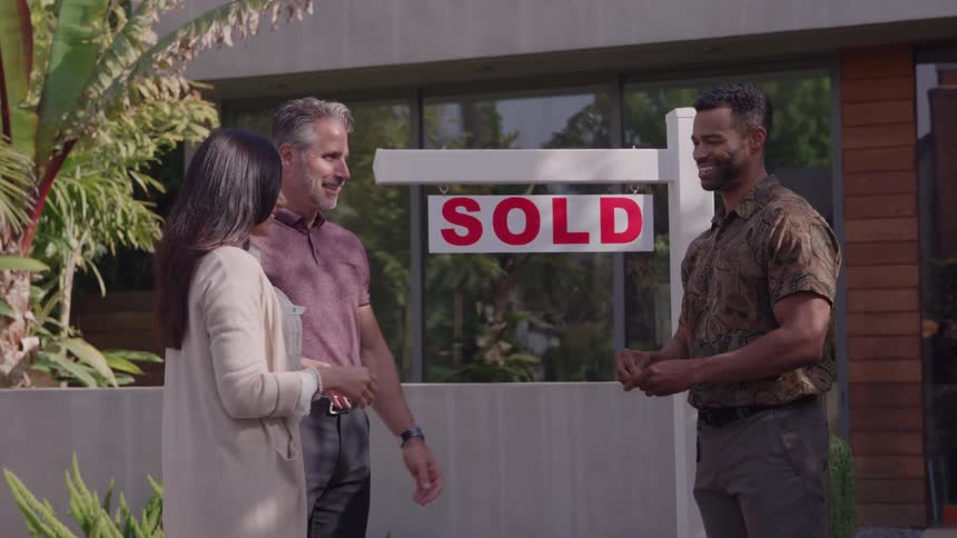 Real estate agent congratulating and handing over keys to his excited home buyers
