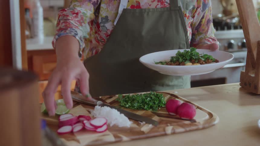 Woman garnishes an entree while standing in the kitchen