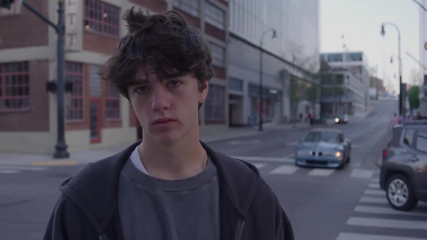 Male teenager standing on an intersection looks up to stare