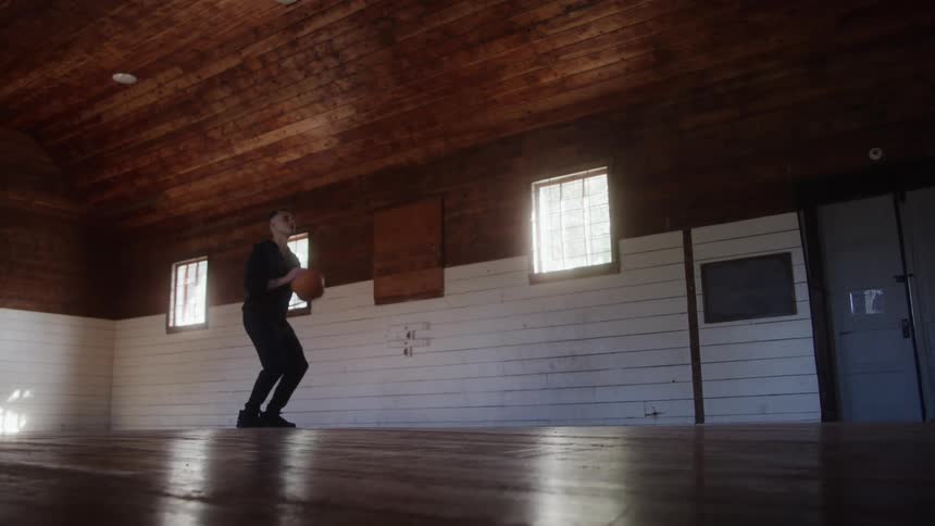 A man plays basketball alone on an indoor court