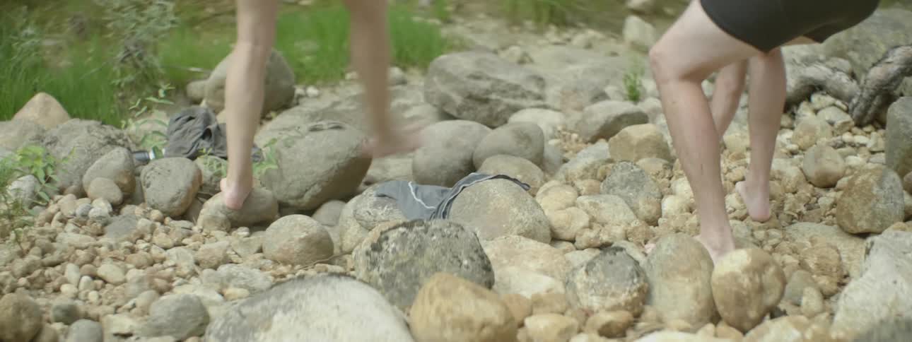 Two people walk over rocks picking some up